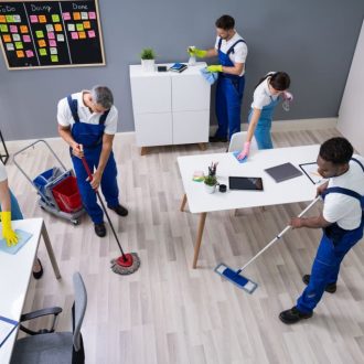 Group Of Janitors In Uniform Cleaning The Office With Cleaning Equipment