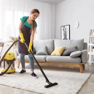 female-janitor-vacuums-living-room